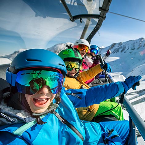 Family skiing in European Alps on a sunny winter day. Mother and kids sitting on chairlift cheering at the camera. Snow capped mountains and glacier ski slopes visible in the background.
Nikon D850