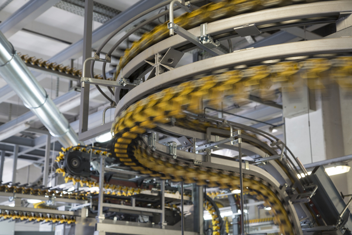 Blurred motion of empty conveyor belts for newspapers and magazines in large modern printing press.