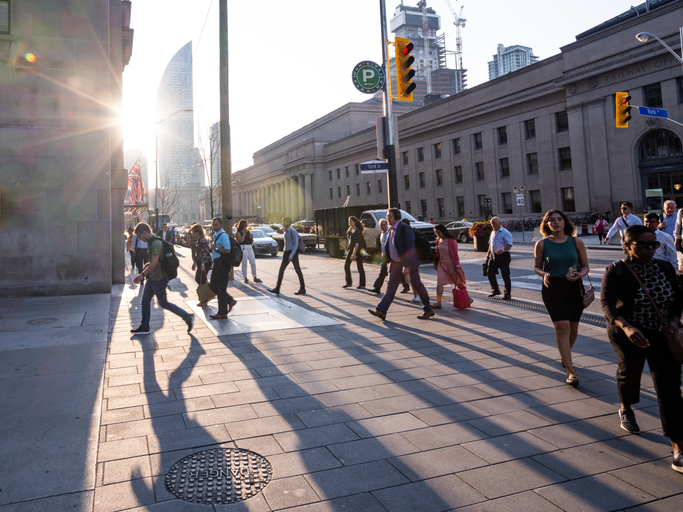 Toronto, Ontario, Canada - July 29, 2019:  The Toronto city skyline during the early morning hours.  It is rush hour and people/commuters are coming into the city, via mass transit, in order to go to work.  Union Station is represented in this photo.  It is the main transportation hub in downtown Toronto.  It is the main hub for Via Rail, a cross Canada rail service and it is also a main hub for other light rail and subway systems.  This is Front Street facing East.