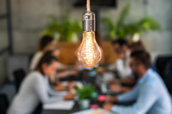 Young business people are discussing together a new startup project. A glowing light bulb as a new idea.