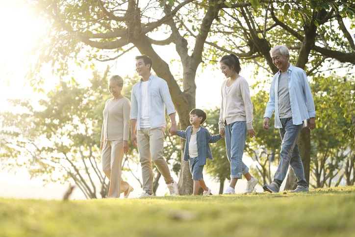 three generation happy asian family walking outdoors in park