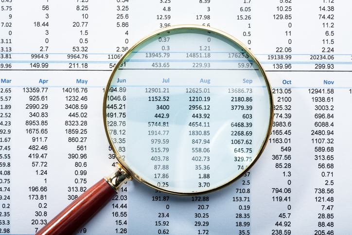 Close-up Of Magnifying Glass On Monthly Financial Report