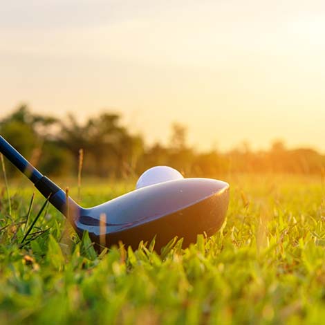 Close up golf ball and driver, player doing golf swing tee off on the green sunset evening time, presumably does exercise. Healthy and Lifestyle Concept. Close up golf ball and driver, player doing golf swing tee off on the green sunset evening time, presumably does exercise. Healthy and Lifestyle Concept.