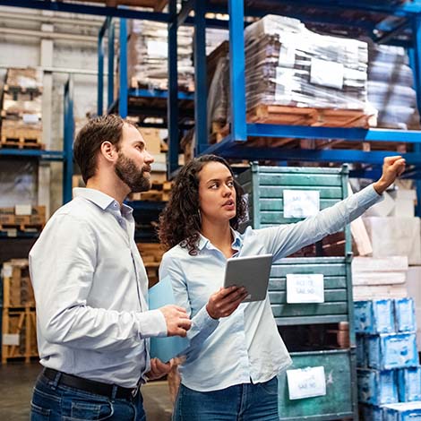 Manager and supervisor taking inventory in warehouse two people reviewing inventory in warehouse