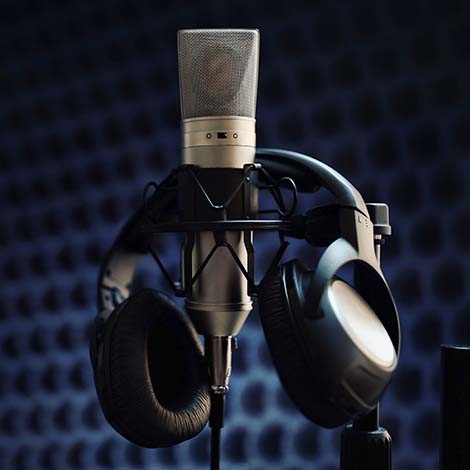 Studio microphone and headphones on mic stand against gray background