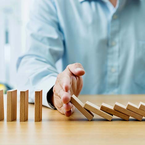 Businessman hand stopping falling blocks on table Businessman hand stopping falling blocks on table.