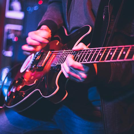 Electric guitar player on a stage with colorful blue and purple scenic illumination