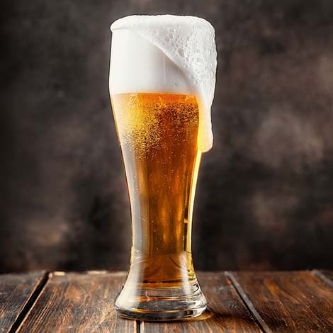 Glass of fresh and cold beer on dark background. Copy space.