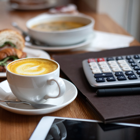 food and coffee next to a calculator and tablet
