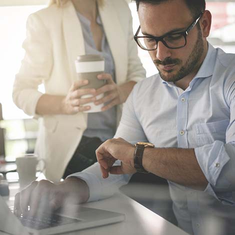 man with laptop looking at wrist watch