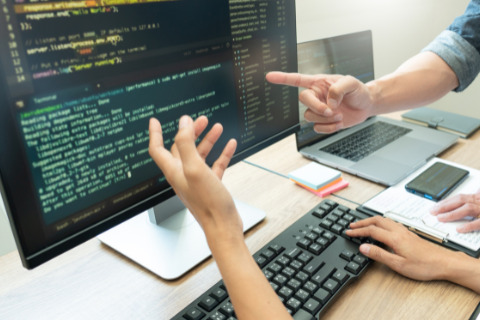 Two sets of hands debating software coding on a desktop