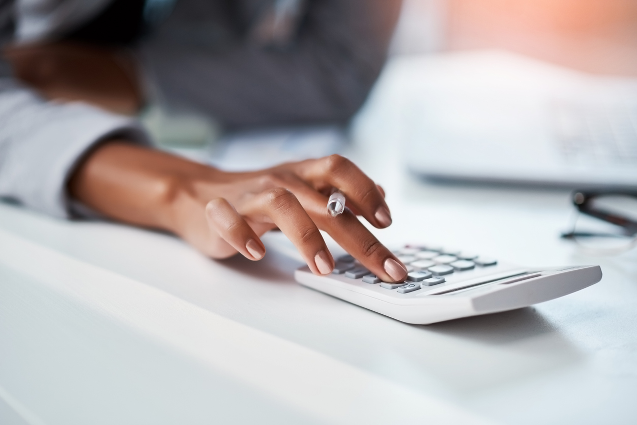 Cropped shot of a businesswoman using a calculator at her desk in a modern office