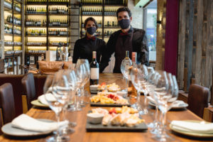 Sommeliers hosting a winetasting event at a cellar wearing facemasks