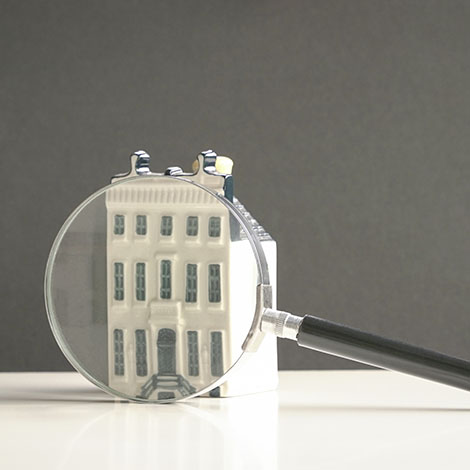 Mini property with magnifying glass. Search for property concept.