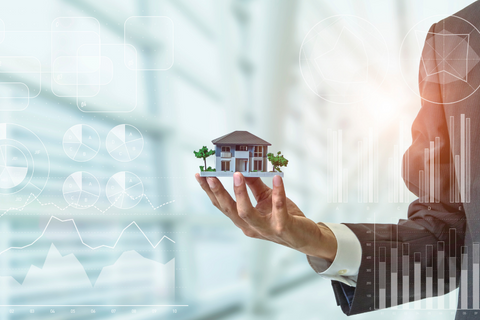 Suited man holding a model of a house in his hands