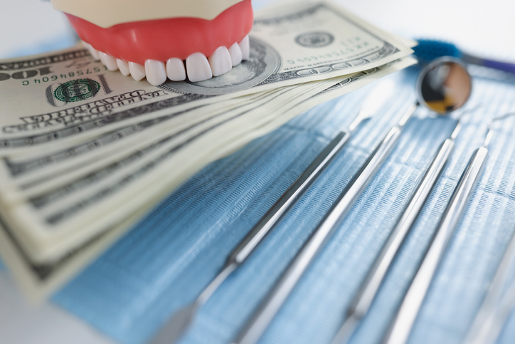 Dentist tools with dollar bills and model of teeth
