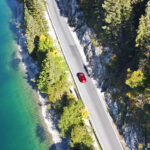 car driving down a road in between water and trees