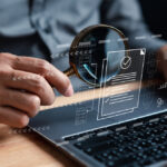 Close up view of a person holding a magnifying glass against a laptop screen