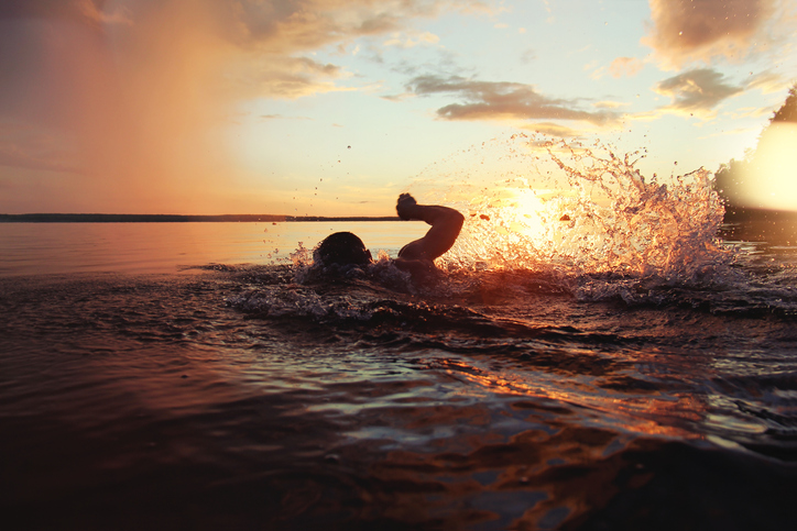 Person swimming in a lake at sunset