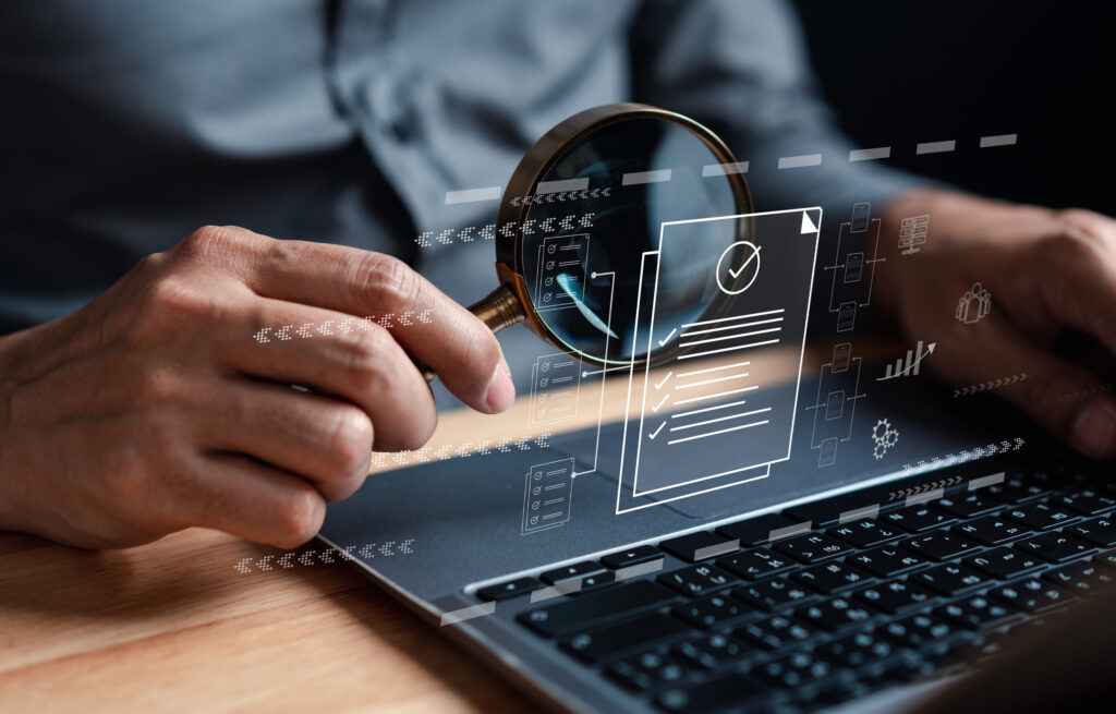 Data analysis concept stock photo - Man holding a magnifying glass over a laptop