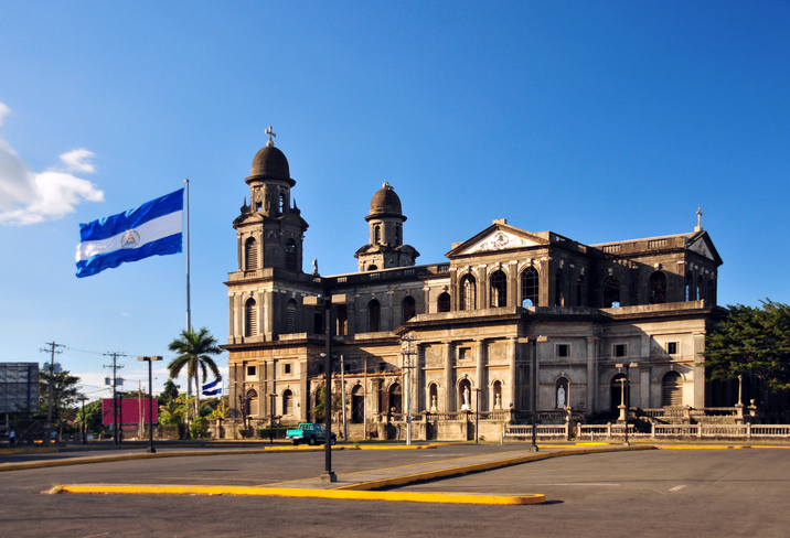 Managua, Nicaragua: south side of the Old Cathedral and the giant Nicaraguan flag flying at Plaza de la Revolución / Plaza de la República, built in concrete and steel and designed by the engineer Pablo Dambach, manufactured and shipped from Belgium, but very damaged by the 1972 earthquake - Antigua Catedral de Santiago de Managua - centro histórico - photo by M.Torres