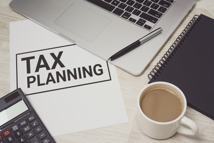 Tax Planning written on white paper with laptop computer and coffee cup. Business and finance concept.