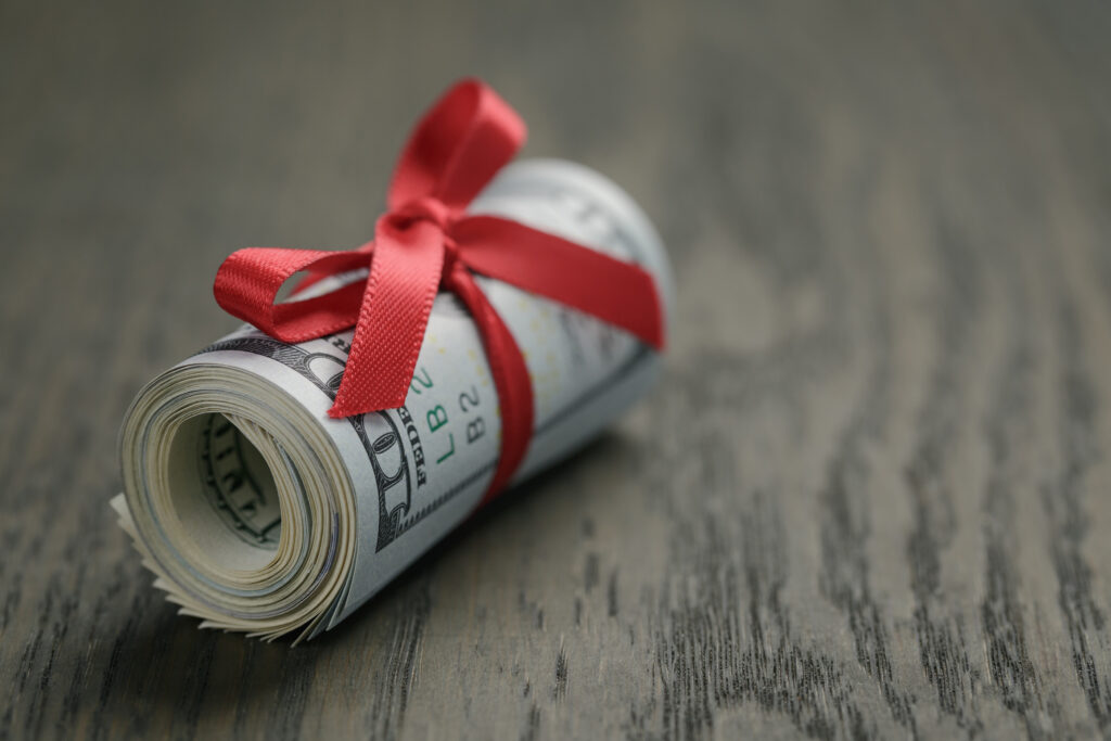 Roll of hundred dollar bills on wooden table
