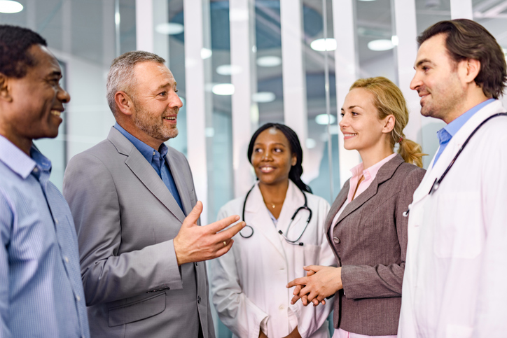 Happy business people talking to doctors in hospital.