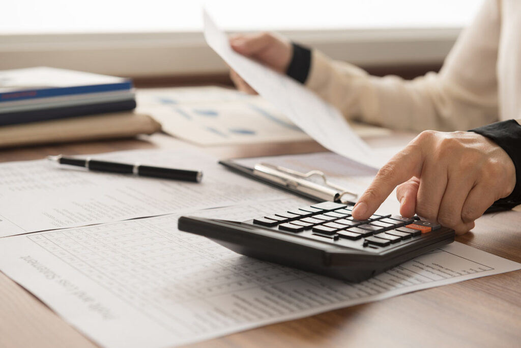 Close up of accountant working on documents with a calculator.