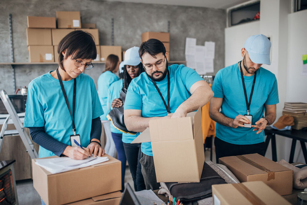 Diverse volunteers packing donation boxes in charity food bank - stock photo