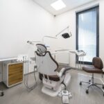 Dental clinic or practice, dental office interior with no people. Treatment room with dental chair, light, dental instruments.