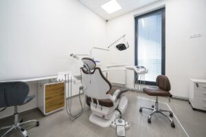 Dental clinic or practice, dental office interior with no people. Treatment room with dental chair, light, dental instruments.