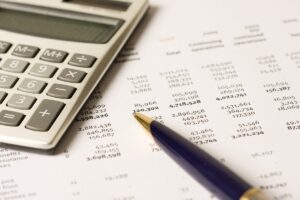 Calculator and pen on stack of financial documents