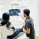Dentist Showing Patient X-Ray Of Teeth After Check Up