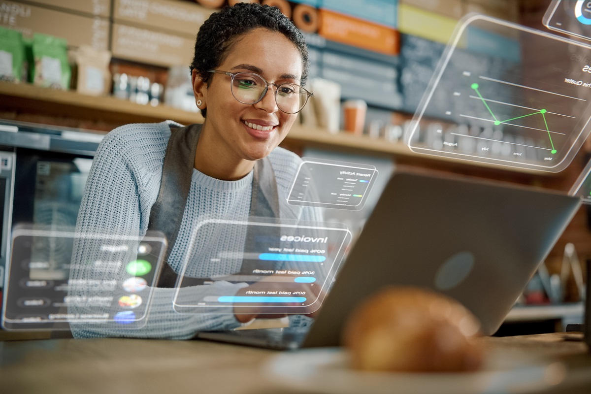Shop Owner is Working on Laptop Computer and Checking Inventory in Cozy Cafe. Restaurant Manager Browsing Internet and Chatting with Friends. VFX Augmented Reality Concept.