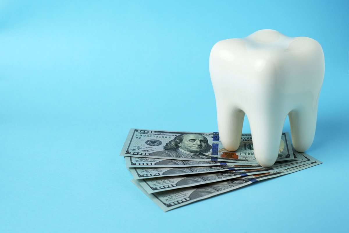 Dollar money bills and tooth model on a blue background with copy space