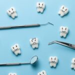 White tooth with caries on blue background and dentist tools mirror, hook