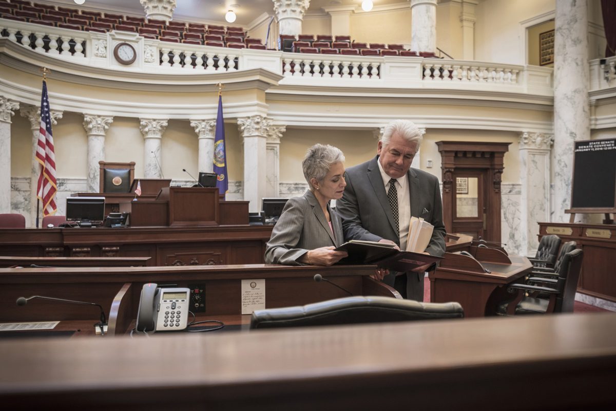 Man and woman stand together in Congressional chambers and review a brief