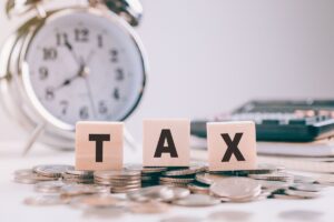 Tax Concept.Word wooden block on coins and Clock with calculator
