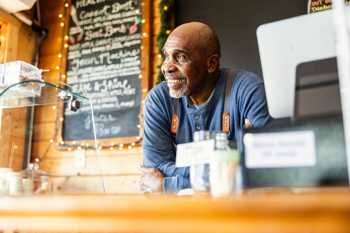 Portrait of senior male cafe owner at front counter