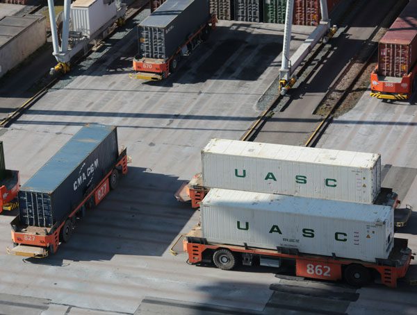 Aerial shot of a shipping center with cargo containers on orange flatbeds