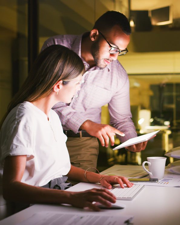 Man and woman sit and stand at a counter and look at something on a tablet