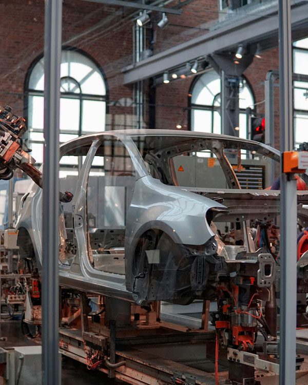 Shot through a glass wall, a car is being assembled by robots