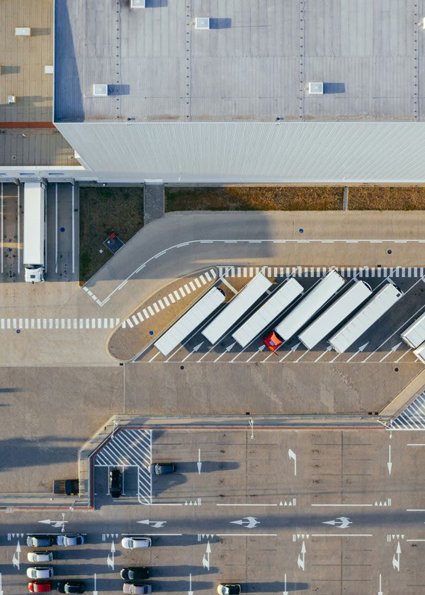 Aerial shot of semi trucks and cars lined up in a shipping center parking lot