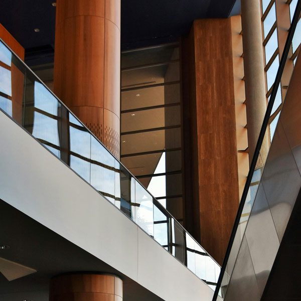 Shot from below, a modern office setting with soaring wood columns, windows, and silver and glass walkways