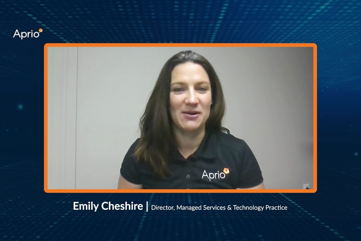A woman wearing an Aprio polo shirt appears on a video call, with a text overlay identifying her as Emily Cheshire, Director, Managed Services & Technology Practice at Aprio.