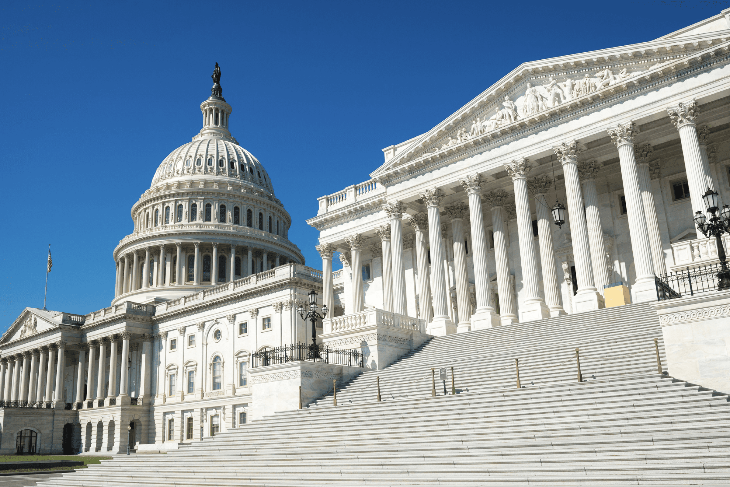The United States Capitol building with its dome, columns, and front steps, photographed under a clear blue sky.