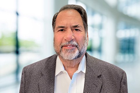 Bearded man in a wool blazer smiles in a bright blurred lobby