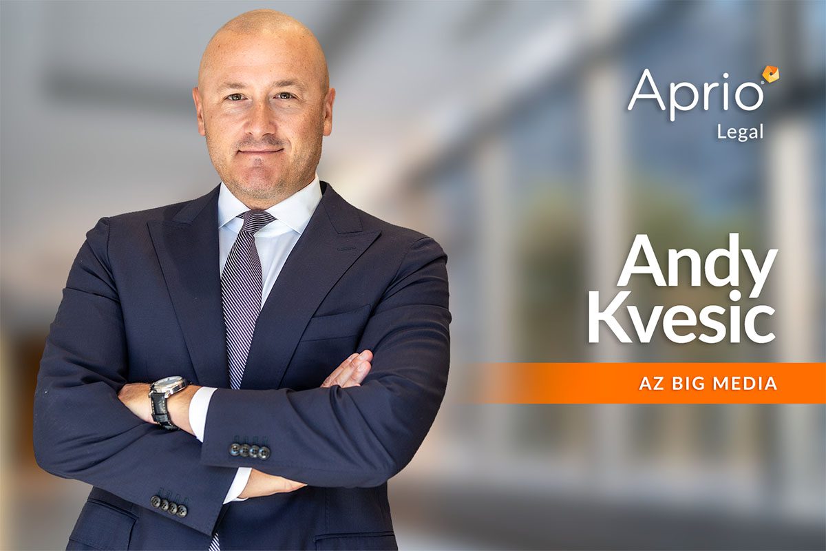A man in a suit stands with arms crossed in front of a blurred office background. Text reads: Aprio Legal, Andy Kvesic, AZ Big Media.