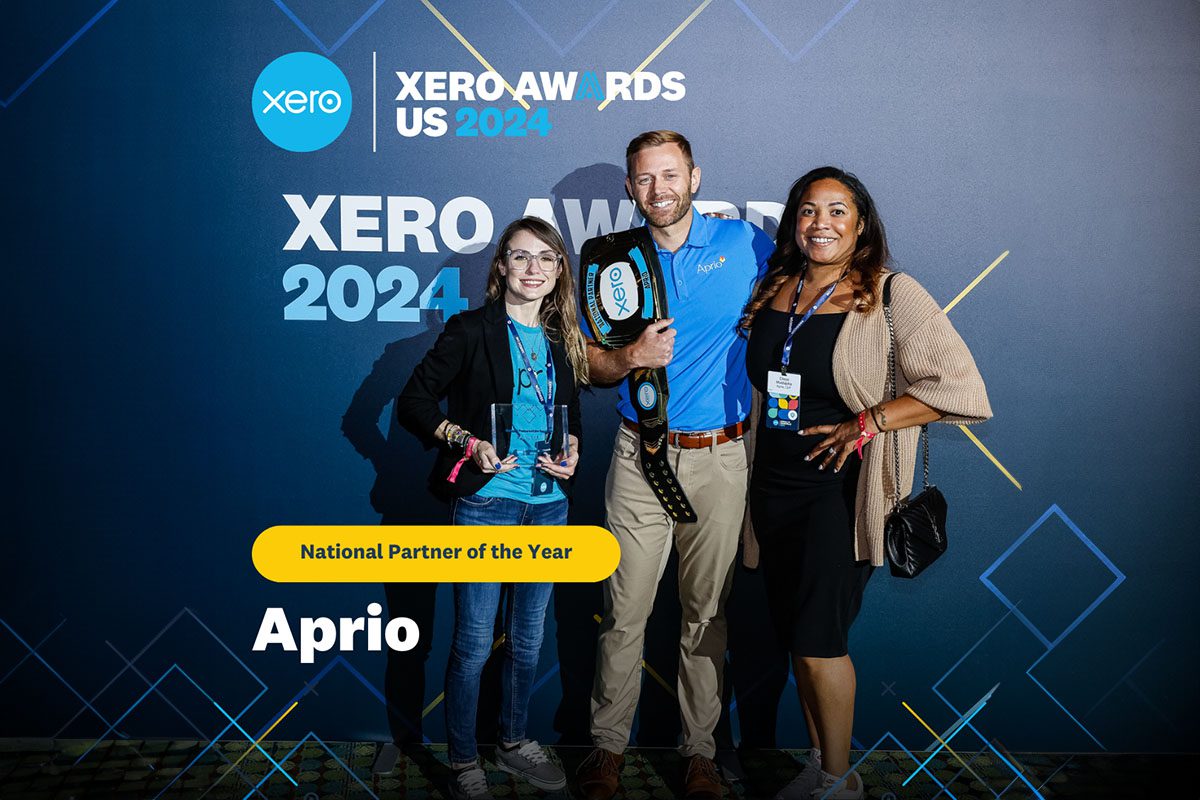 Three people pose with awards in front of a Xero Awards 2024 backdrop. A banner reads National Partner of the Year: Aprio.